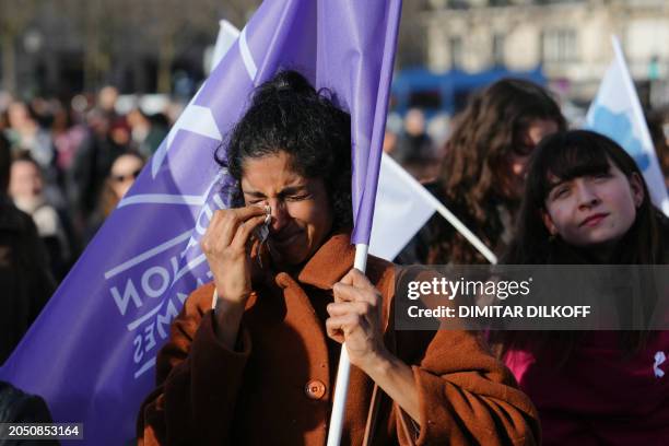 Woman sheds tears as she holds a flag of the "Fondation des Femmes" women's rights group as people gather at the Place du Trocadero in Paris, on...