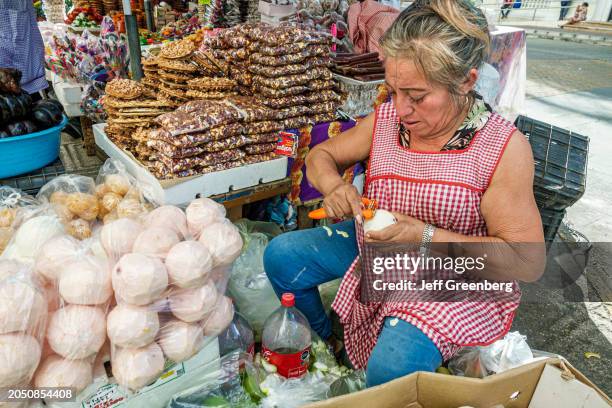 Merida, Mexico, Mercado San Benito, woman peeling Mandarin oranges at market stall.