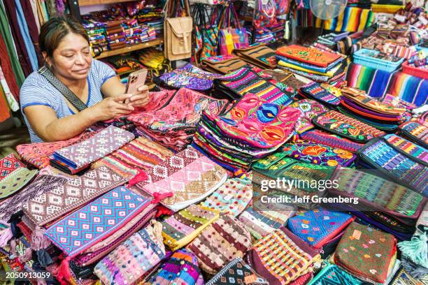 Merida, Mexico, arts & crafts souvenir store, embroidered handbags bags purses, woman on smartphone.