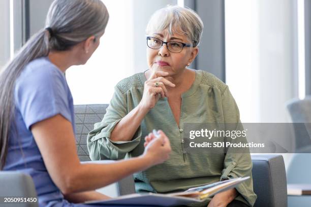 senior woman listens carefully as female doctor explains diagnosis - språk bildbanksfoton och bilder