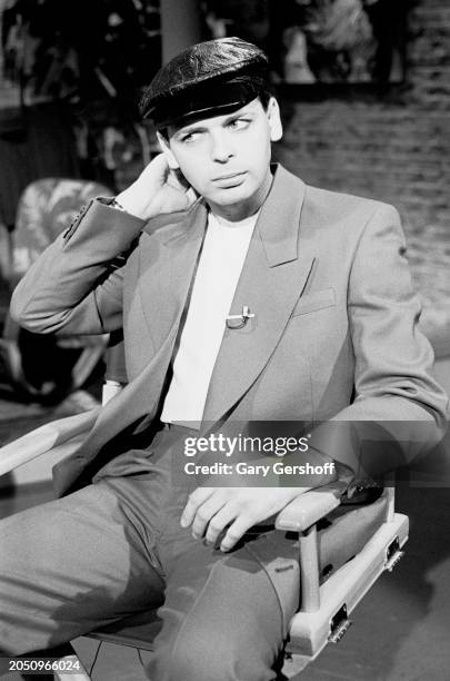 View of British New Wave musician Gary Numan as he sits in a director's chair during an interview on MTV at Teletronic Studios, New York, New York,...