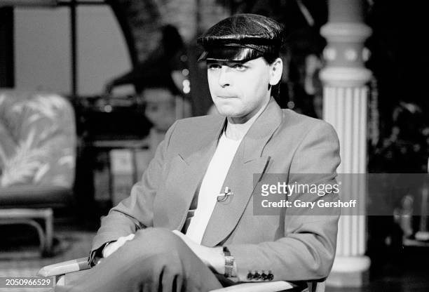 View of British New Wave musician Gary Numan as he sits in a director's chair during an interview on MTV at Teletronic Studios, New York, New York,...
