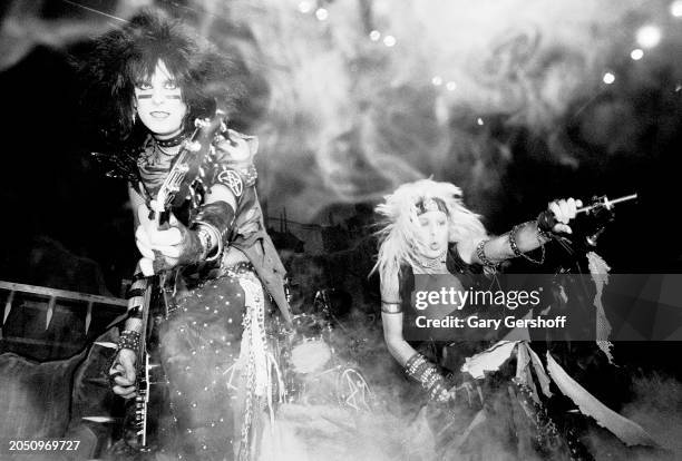 View of American Heavy Metal musicians Nikki Sixx , on bass guitar, and vocalist Vince Neil , both of the group Motley Crue, as they perform onstage,...