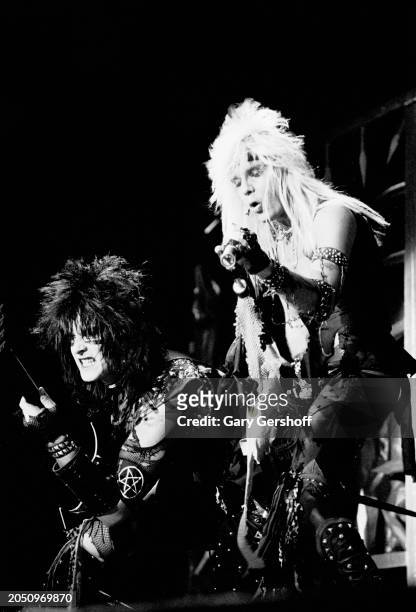 View of American Heavy Metal musicians Nikki Sixx , on bass guitar, and vocalist Vince Neil , both of the group Motley Crue, as they perform onstage,...