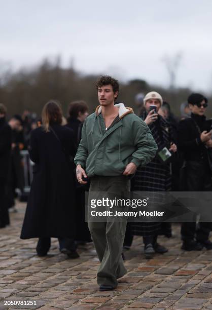 Shawn Mendes seen wearing a gold necklace, khaki green oversized hooded bomber jacket, khaki green corduroy wide leg pants and black leather shoes,...