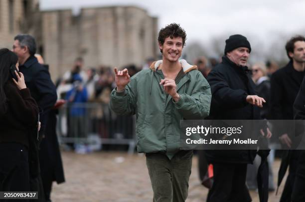 Shawn Mendes seen wearing a gold necklace, khaki green oversized hooded bomber jacket, gold rings and khaki green corduroy wide leg pants, outside...