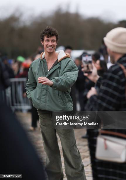 Shawn Mendes seen wearing a gold necklace, khaki green oversized hooded bomber jacket, gold rings and khaki green corduroy wide leg pants, outside...
