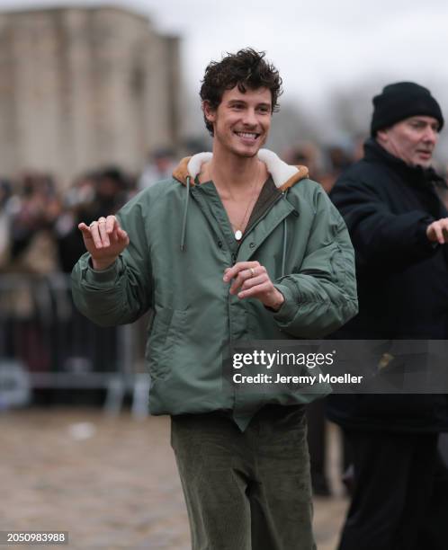 Shawn Mendes seen wearing a gold necklace, khaki green oversized hooded bomber jacket, gold rings and khaki green corduroy wide leg pants, outside...