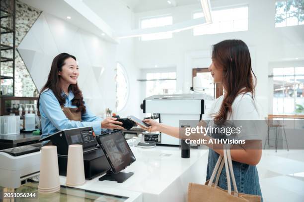 modern retail checkout: customer using smartphone for contactless payment at register - winkelier stockfoto's en -beelden