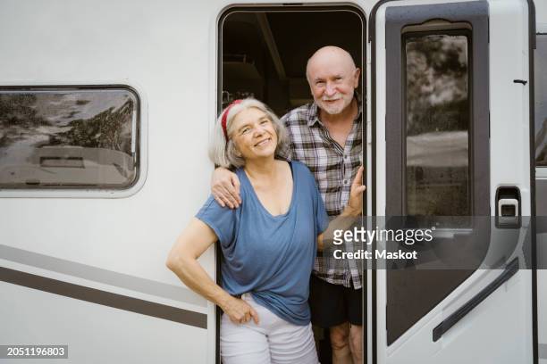 portrait of smiling senior man standing behind woman at motor home doorway - wonderlust stock-fotos und bilder