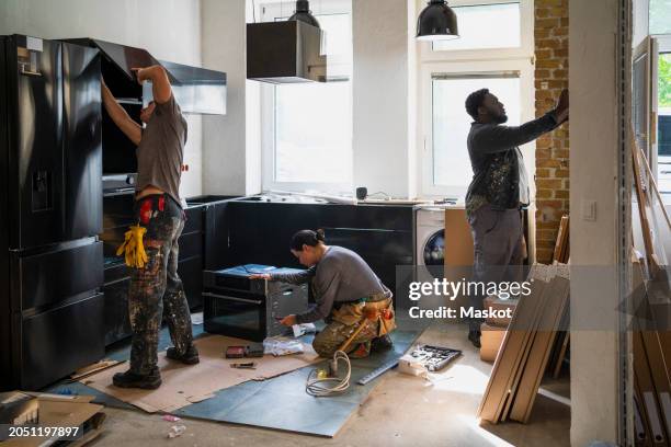 diverse male and female carpenters working in kitchen at site - home interior renovations stock pictures, royalty-free photos & images