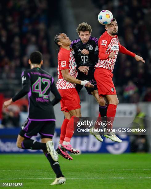 Thomas Mueller of Munich jumps for header against Kiliann Sildillia and Manuel Gulde of Freiburg during the Bundesliga match between Sport-Club...