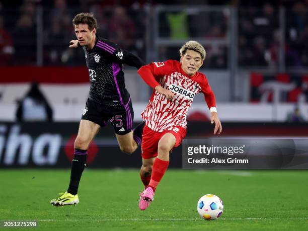 Ritsu Doan of SC Freiburg runs with the ball whilst under pressure from Thomas Mueller of Bayern Munich during the Bundesliga match between...