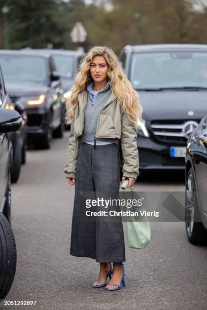 Emili Sindlev wears cropped grey jacket, Loewe squeeze bag, high waisted grey pants, blue heels, grey jumper outside Loewe during the Womenswear...