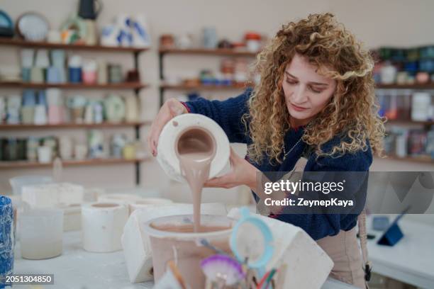 woman making ceramic pots in the ceramic workshop, pouring clay into the molds. - earthenware stock pictures, royalty-free photos & images
