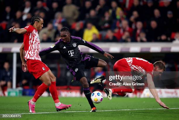 Mathys Tel of Bayern Munich is challenged by Kiliann Sildillia and Matthias Ginter of SC Freiburg during the Bundesliga match between Sport-Club...