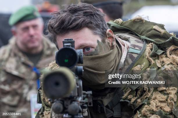 British soldier looks into a telescopic sight as he holds his sniper rifle during the NATO DRAGON-24 military exercise in Korzeniewo, northern...
