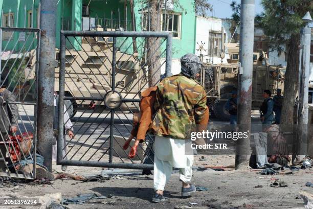 An Afghan man carries a victim of a suicide attack in Maymana city of Faryab province, north of Kabul on April 4, 2012 . A suicide bomber attacked...