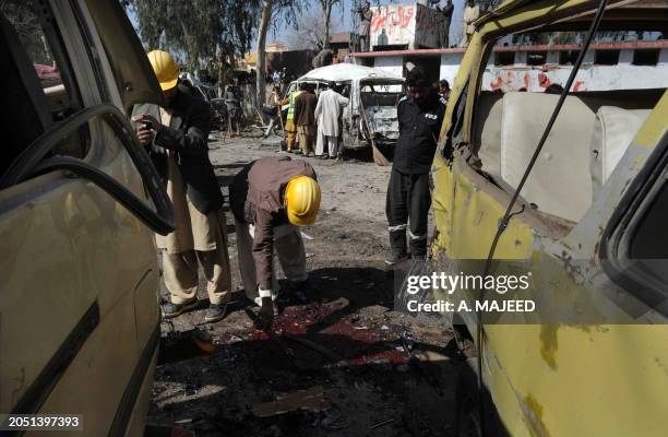 Pakistani volunteers search the site of a car blast on the outskirts of Peshawar on February 23, 2012. A car bomb ripped through a Pakistani bus...