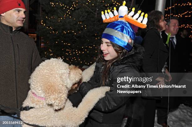 Ella Kasper of Delmar wears a menorah hat as she plays with her Golden Doodle dog named Doodle at a lighting of the menorah for Bethlehem Chabad's...