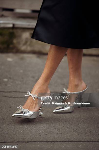 Tamu McPherson wears long black coat, and silver pointy high heels outside Giambattista Valli during the Womenswear Fall/Winter 2024/2025 as part of...
