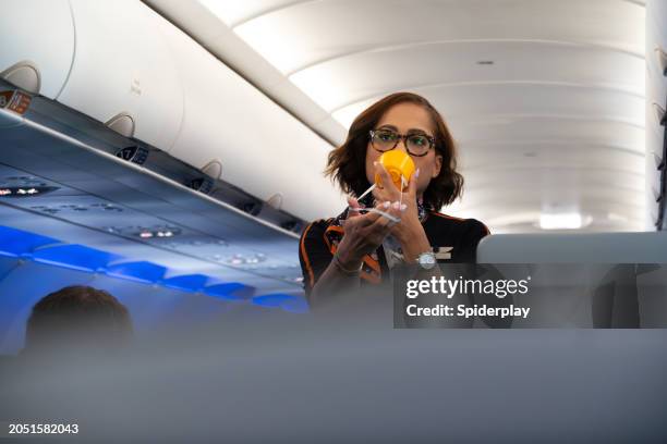 flight stewardess giving a safety tutorial in airplane aisle - cabinepersoneel stockfoto's en -beelden