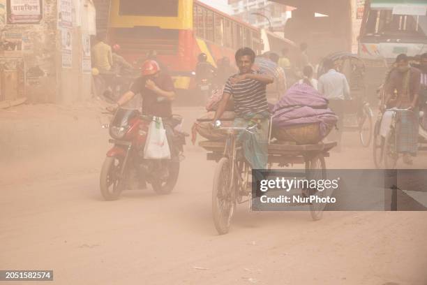 People are crossing the street wearing masks and covering their faces with their hands as dust covers the road in Sayedabad, Dhaka, Bangladesh, on...