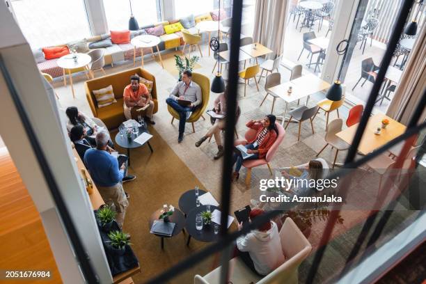 overhead-ansicht eines geschäftstreffens, bei dem die verschiedenen mitarbeiter die unternehmensstrategie diskutieren - kantine stock-fotos und bilder