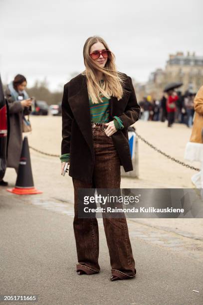 Pernille Teisbaek wears brown jeans, green and pink striped top, and orange sunglasses outside Loewe during the Womenswear Fall/Winter 2024/2025 as...