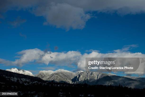 the oceanside coastal community of west vancouver, british columbia, canada situated in burrard inlet and the georgia straight of the pacific ocean with the towering coastal mountain range and cypress behind it, over the lions gate bridge to vancouver - cypress mountain foto e immagini stock