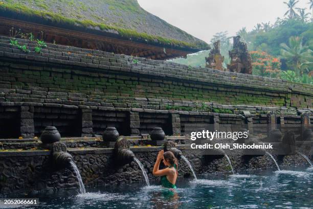 mujer haciendo ritual purificador en la primavera sagrada de tirta empul - bali fotografías e imágenes de stock