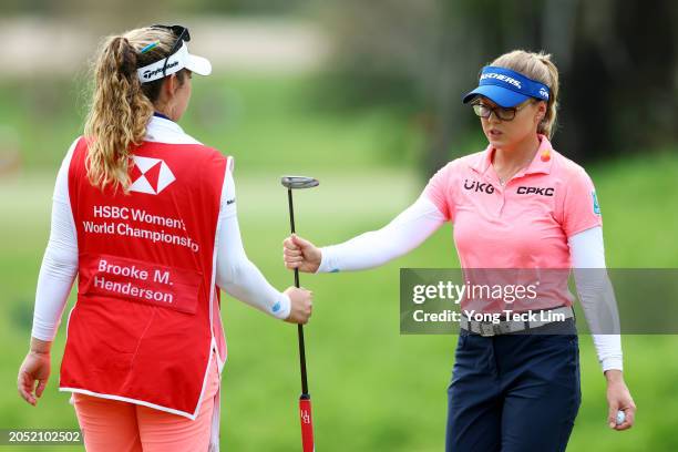 Brooke Henderson of Canada passes her putter to her sister and caddie Brittany Henderson after putting on the eighth green during Day Three of the...