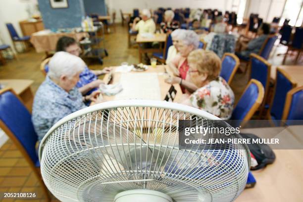 Des personnes âgées jouent au scrabble à proximité d'un ventilateur en raison des fortes chaleurs qui sévissent dans la région, le 04 juillet 2006 au...