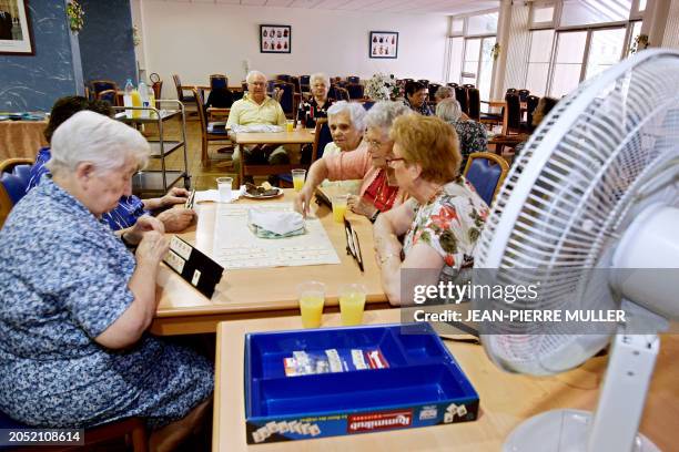 Des personnes âgées jouent au scrabble à proximité d'un ventilateur en raison des fortes chaleurs qui sévissent dans la région, le 04 juillet 2006 au...