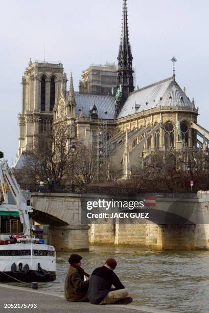 Deux personnes profitent des températures particulièrement douces pour la saison sur un quai de la Seine face à Notre-Dame-de-Paris, le 05 février...