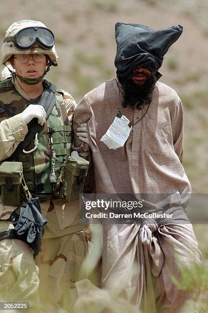 Military Police officer from the 82nd Airborne takes an Afghan prisoner into custody during Operation Dragon Fury June 2, 2003 in eastern...