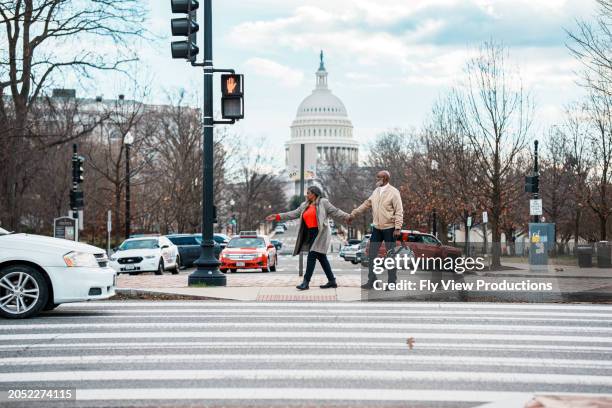 african american couple walking hand in hand along the street in washington dc - couple crossing street stock pictures, royalty-free photos & images