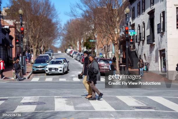 active senior couple crossing the street while exploring washington dc in the winter - couple crossing street stock pictures, royalty-free photos & images