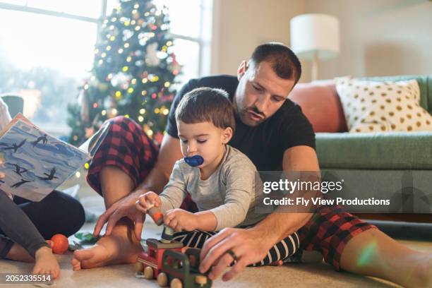 niño pequeño multirracial y su papá jugando con juguetes en casa en navidad - padre soltero fotografías e imágenes de stock