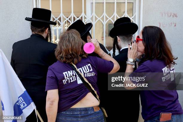 Israeli protesters jeer at Ultra-Orthodox Jewish men outside an army recruiting office in the town of Kiryat Ono near Tel Aviv on March 5 during a...