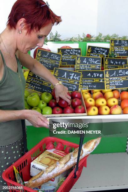 Marie-Lise Fleurette, coiffeuse, se familiarise à l'euro devant un étalage de fruits dont les prix sont affichés en euro, le 20 juin 2001 d'Epinal,...