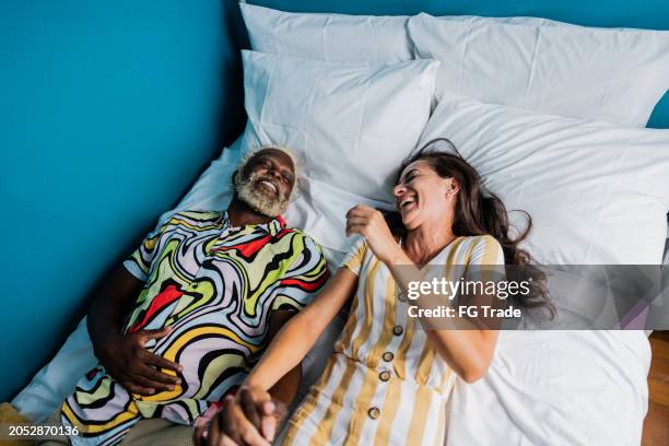 happy couple lying on bed on hotel room - guest bedroom stock pictures, royalty-free photos & images