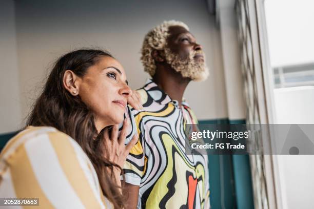 couple looking through window at home - couple dreaming stock pictures, royalty-free photos & images