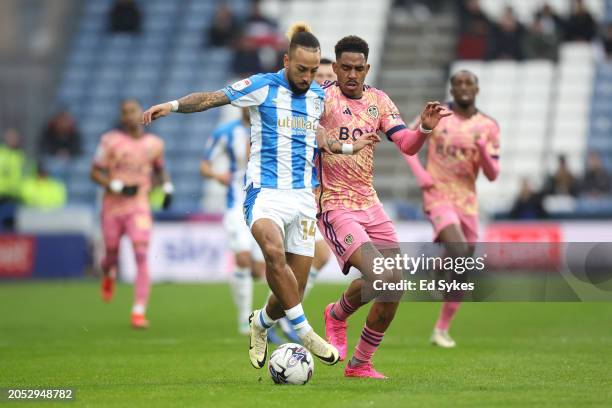 Sorba Thomas of Huddersfield Town runs with the ball whilst under pressure from Junior Firpo of Leeds United during the Sky Bet Championship match...