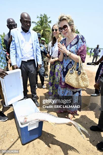 Queen Mathilde of Belgium inspects the catch of a fisherman, during a royal visit to Grand-Lahou and its cemetery, during a royal working visit to...