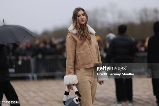 Zita d'Hauteville was seen wearing beige pants, cropped beige jacket with white fluffy ends as well as a animal shaped grey black and white bag...