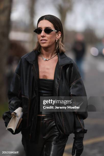 Fashion week guest is seen wearing dark Celine shades, a white bag and all black outfit including hand gloves,cropped top, jacket and pants before...