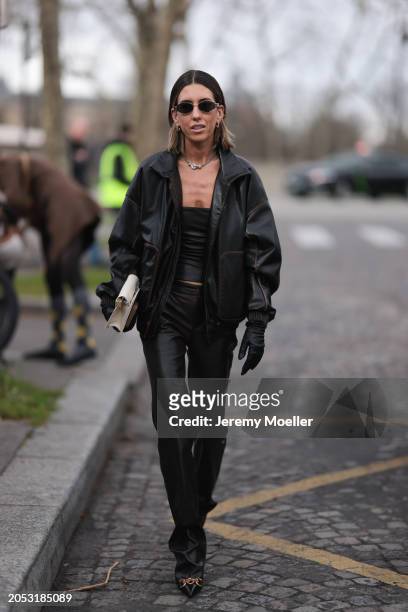 Fashion week guest is seen wearing dark Celine shades, a white bag and all black outfit including hand gloves, shoes, cropped top, jacket and pants...