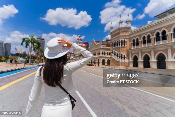 asian woman tourist in white dress and white hat standing in front of sultan abdul samad building. kuala lumpur - abdul stock pictures, royalty-free photos & images