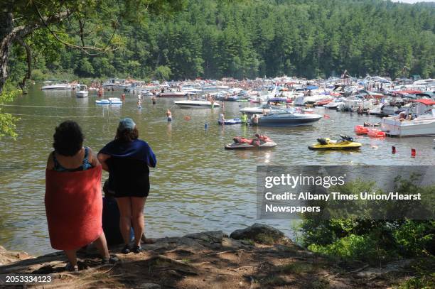 Rosanne Whitton of St. James, left, and her sister Donna Hay of Farmingville watch people party and swim in Log Bay on Lake George on Monday, July...